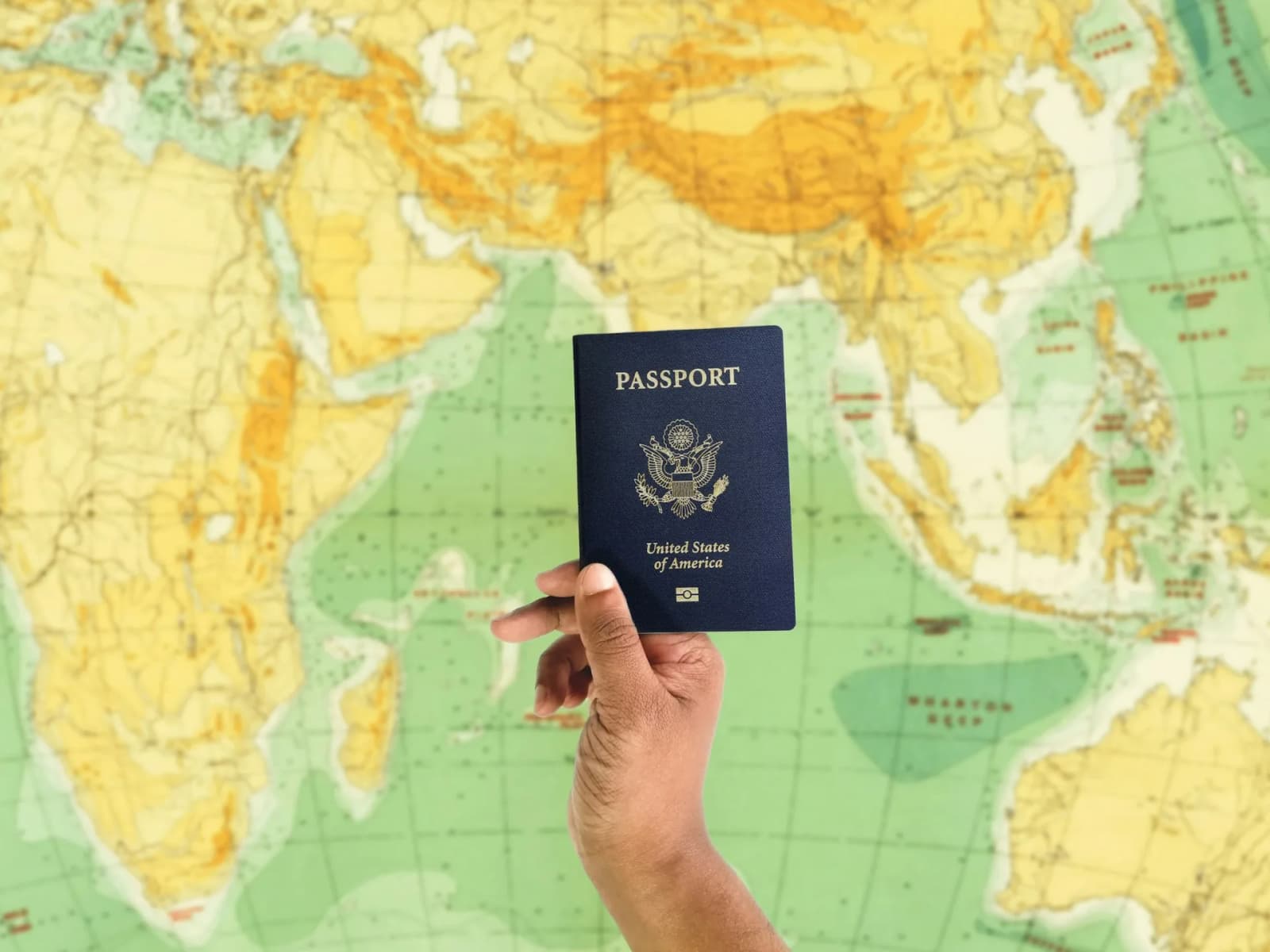 Hand holding passport against world map